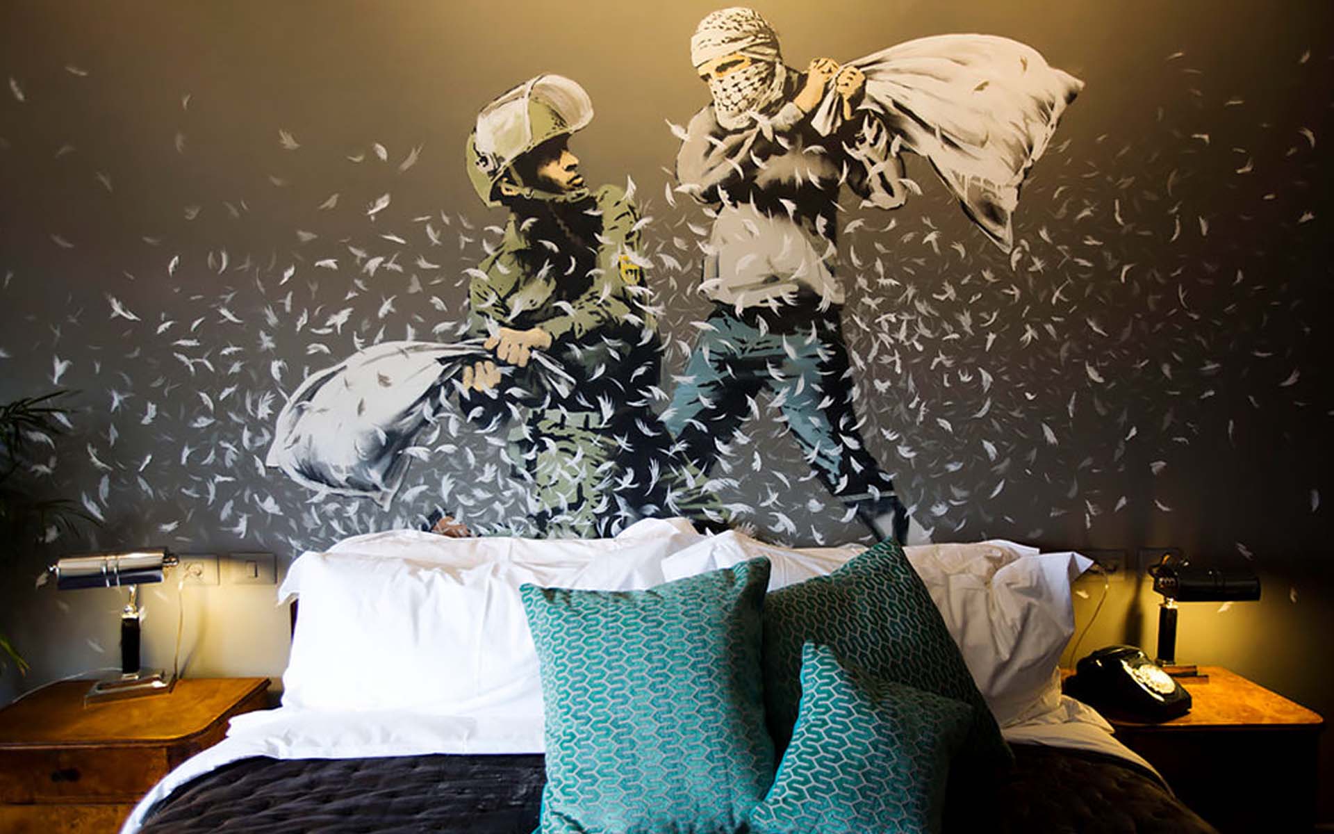 A hotel bedroom with a large stencilled mural filling the wall behind the bed