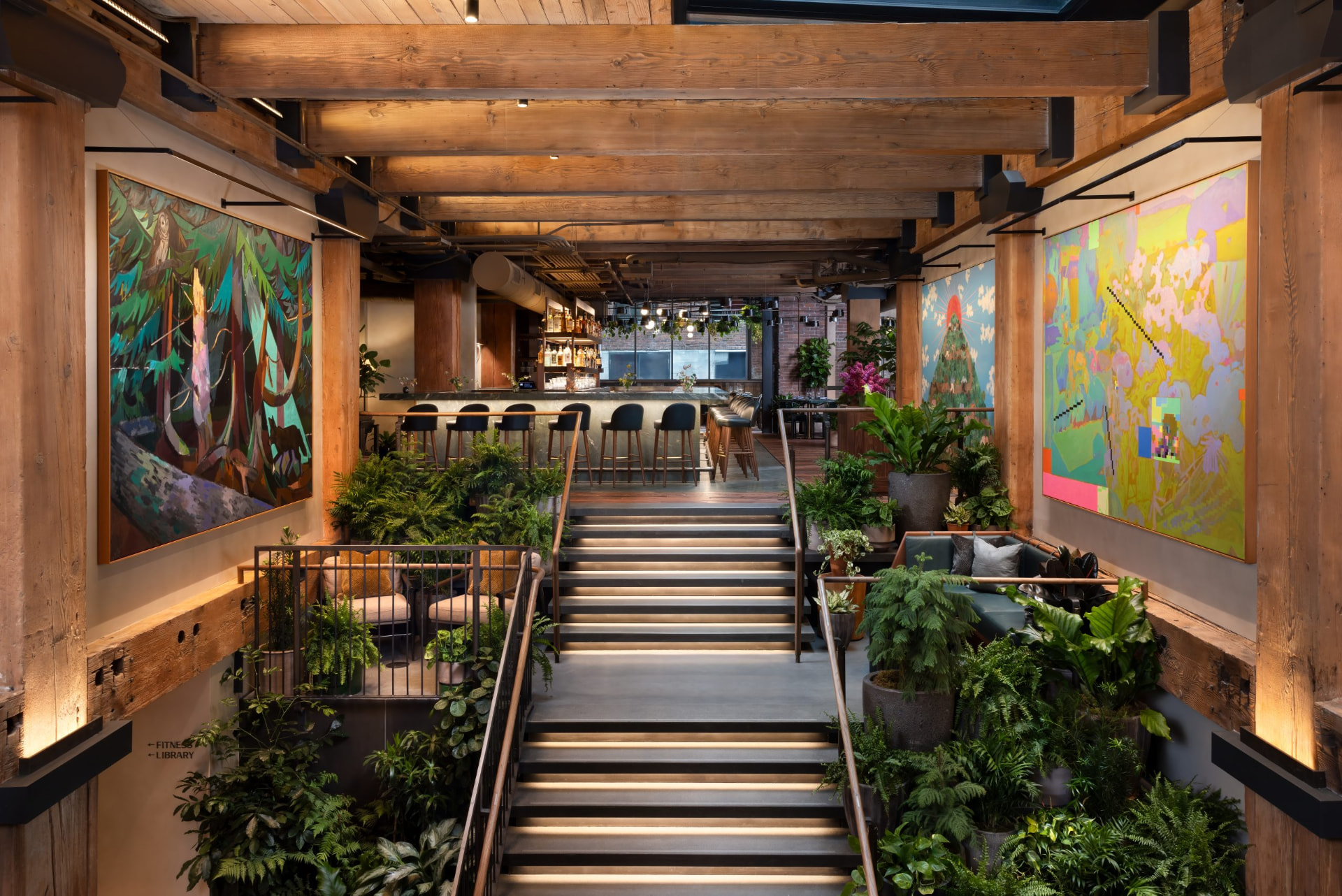 A hospitality interior with large contemporary paintings hung between timber columns
