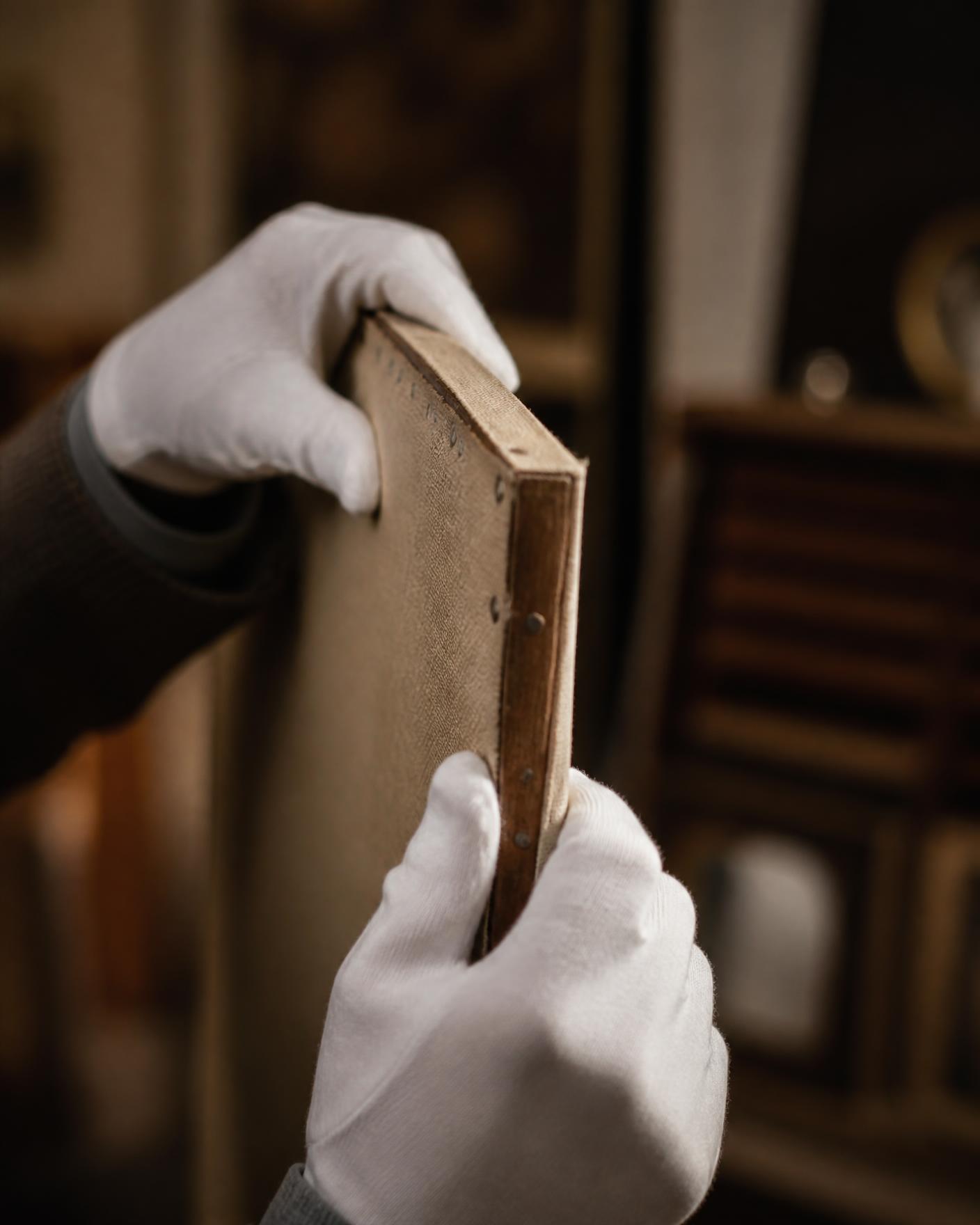 White-gloved hands inspecting the stretcher of an antique canvas